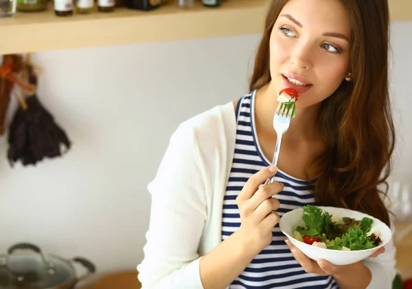 Mujer joven comiendo ensalada y sosteniendo una ensalada mixta — Foto de Stock