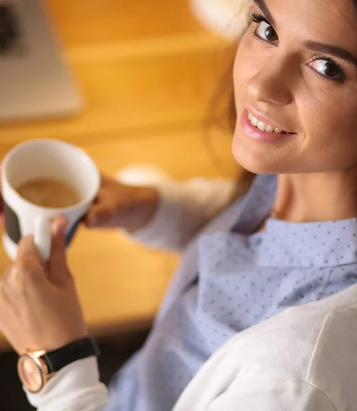 Ritratto di giovane donna rilassata seduta alla scrivania con in mano una tazza di caffè — Foto Stock