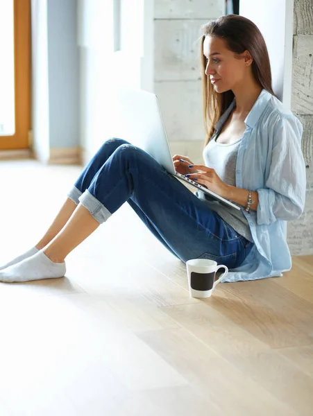 Молодая красивая женщина дома сидит на полу с ноутбуком — стоковое фото