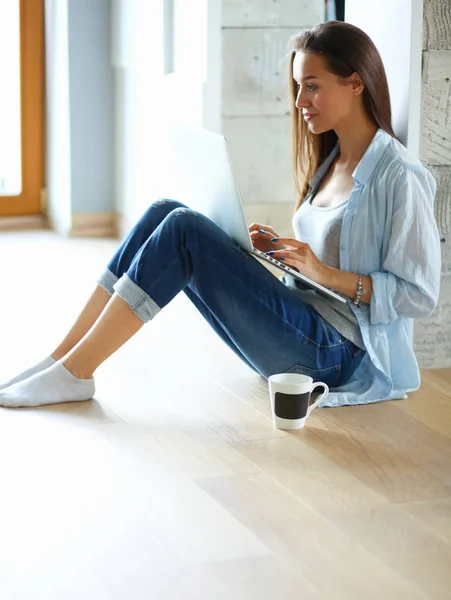 Unga vackra kvinnan hemma sitter på golvet med laptop — Stockfoto