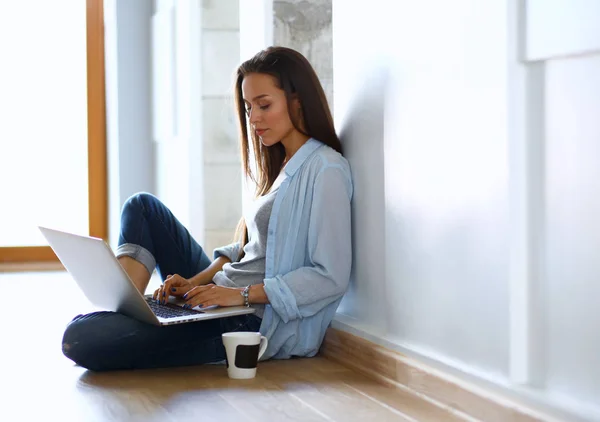 Joven hermosa mujer en casa sentada en el suelo con el ordenador portátil — Foto de Stock