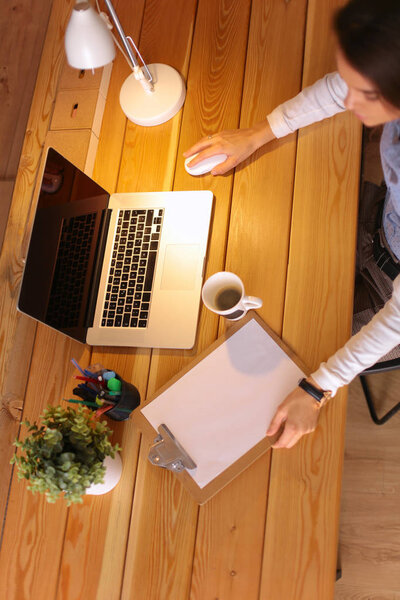 Portrait relaxed young woman sitting at her desk holding cup of coffee