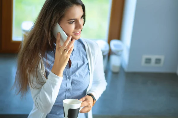 Lycklig kvinna dricka te i köket hemma och prata i telefon — Stockfoto