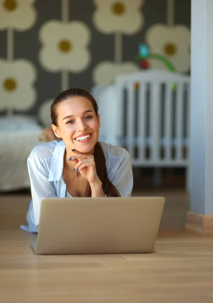 Jeune belle femme à la maison couchée sur le sol avec ordinateur portable — Photo