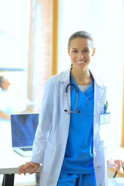 Woman doctor standing at hospital near desk — Stock Photo, Image