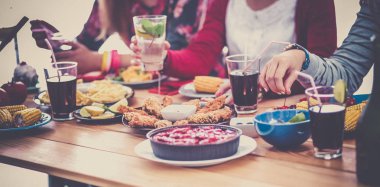 Bir grup insan ahşap masada otururken birlikte yemek yiyorlar.