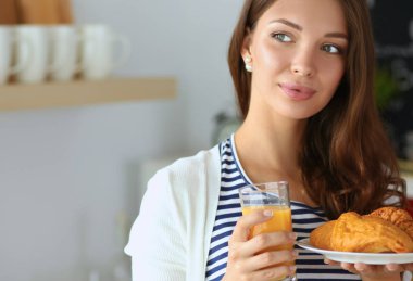 Bir bardak meyve suyu ve keki olan genç bir kadın.