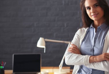 Dizüstü bilgisayarının yanında duran genç bir kadın.