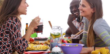 Bir grup insan ahşap masada otururken birlikte yemek yiyorlar.