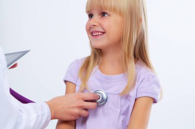 Kadın doktor ameliyatta steteskopla çocuğu muayene ediyor.