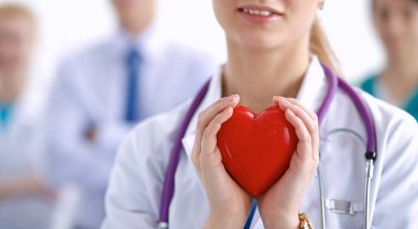 Kırmızı bir kalp taşıyan genç bir kadın doktor, beyaz arka planda izole edilmiş.