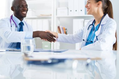 Ofiste tokalaşırken gülümseyen iki genç doktor.