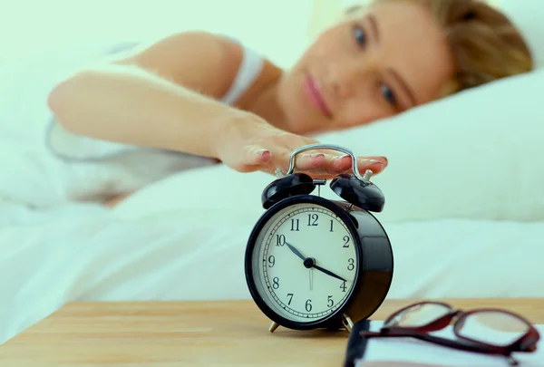 Jeune femme endormie et réveil dans la chambre à coucher à la maison — Photo