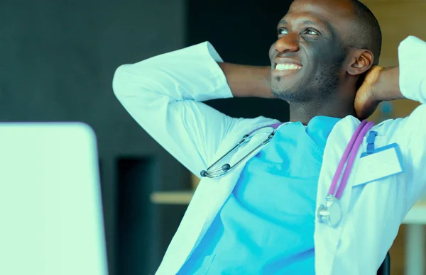 Jeune médecin africain travaillant sur ordinateur portable au bureau — Photo