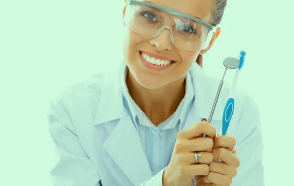 Vacker kvinnlig tandläkare håller och visar tandborste isolerad på en vit bakgrund — Stockfoto