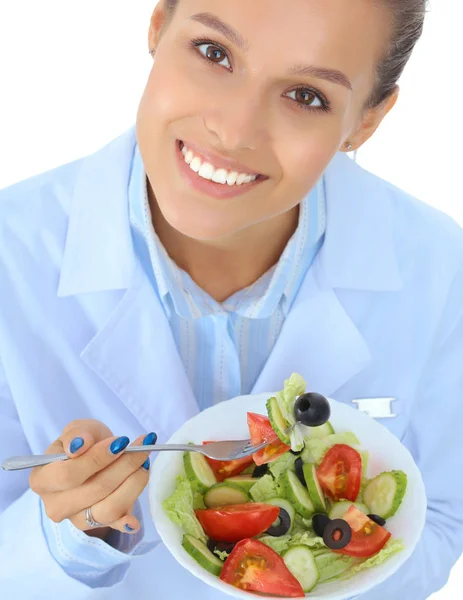 Portrait d'une belle femme médecin tenant une assiette avec des légumes frais. — Photo