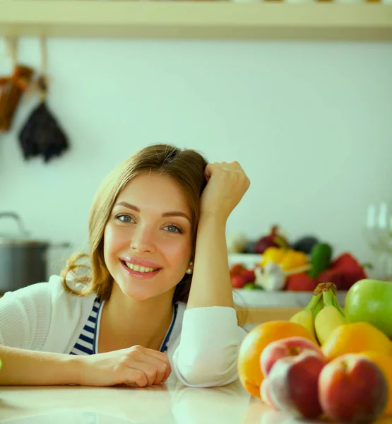 Jonge vrouw in de buurt van bureau in de keuken — Stockfoto