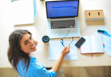 Dizüstü bilgisayar ekranına bakarak office tablosunda oturan genç kadın