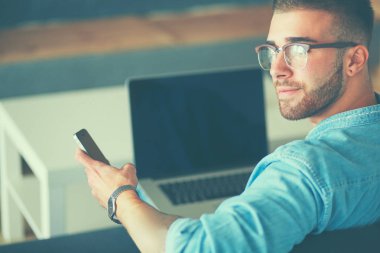 Genç adam kullanarak telefon ve dizüstü bilgisayarda çalışır