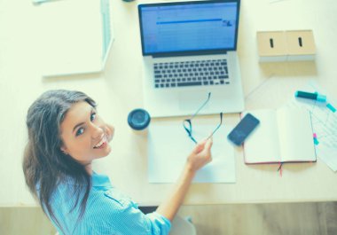 Dizüstü bilgisayar ekranına bakarak office tablosunda oturan genç kadın