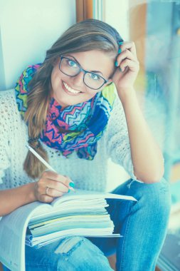 Kitapların arasında masa başında oturan genç bir kadın.