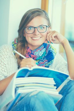 Kitapların arasında masa başında oturan genç bir kadın.