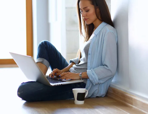 Молода красива жінка вдома сидить на підлозі з ноутбуком — стокове фото
