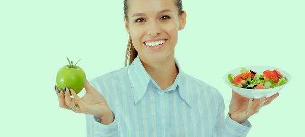 Портрет красивої жінки-лікаря, що тримає тарілку зі свіжими овочами та зеленим яблуком — стокове фото