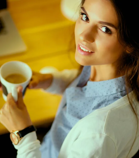 Retrato mujer joven relajada sentada en su escritorio sosteniendo taza de café —  Fotos de Stock