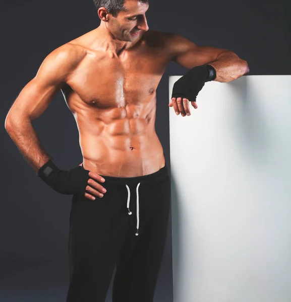 Сильний атлетичний чоловік стоїть біля дошки на чорному тлі — стокове фото