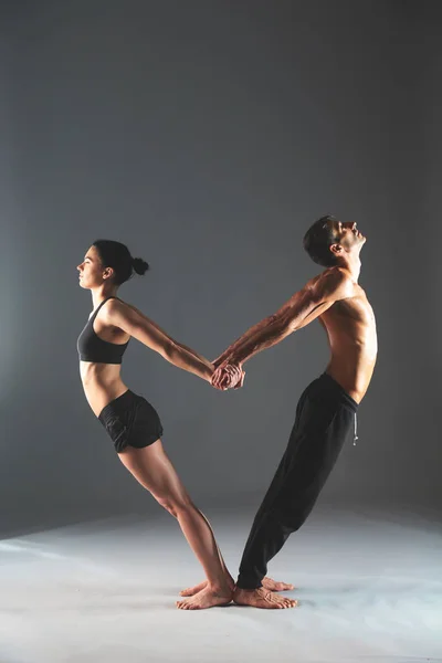 Casal jovem praticando acro ioga no tapete em estúdio juntos — Fotografia de Stock