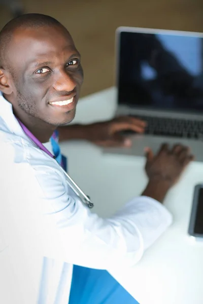 Joven médico africano trabajando en portátil en el escritorio — Foto de Stock