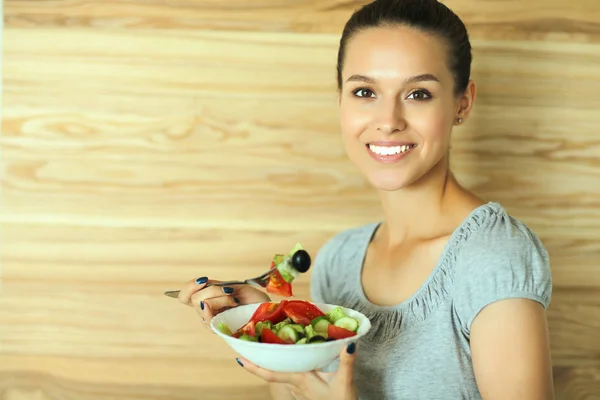 Beautiful girl eating healthy food on wooden background — Stock Photo, Image