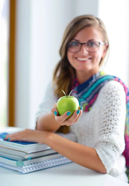애플과 함께 책상에 앉아 책 더미 여성 대학생 — 스톡 사진