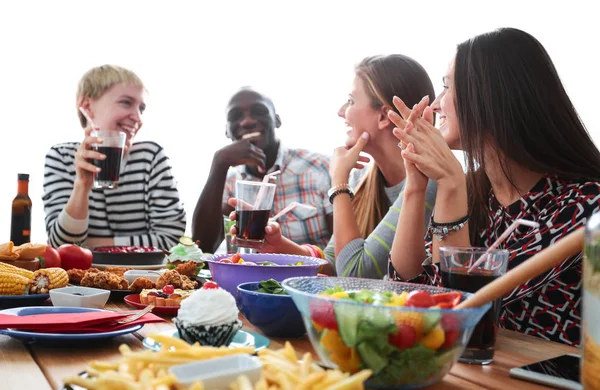 Grupo de pessoas jantando juntas enquanto sentadas à mesa de madeira — Fotografia de Stock