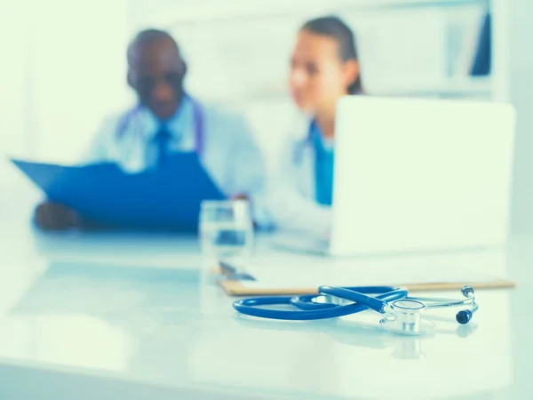 Stethoscoop op het bureau en jonge medische mensen als achtergrond — Stockfoto