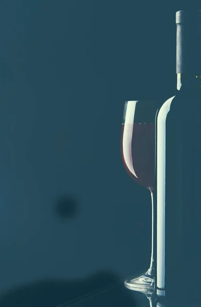 Copo de vinho e uma garrafa no fundo preto — Fotografia de Stock