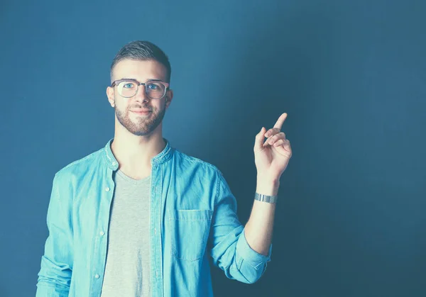 Portret van een glimlachende jonge man die omhoog wijst — Stockfoto