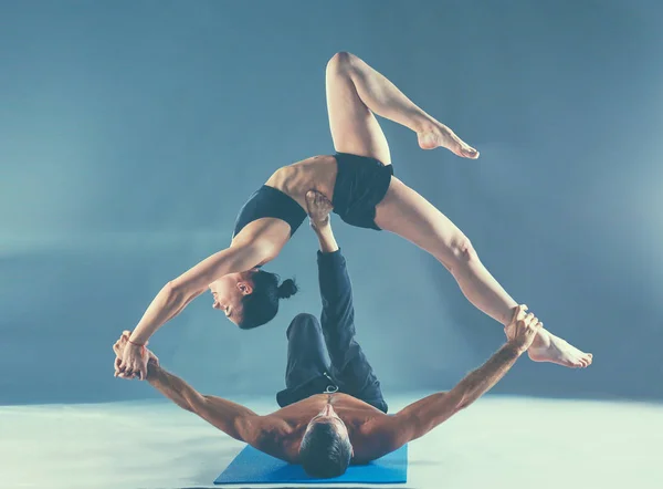 Young couple practicing acro yoga on mat in studio together — Stock Photo, Image