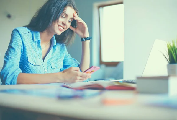 Young woman sitting at office table with laptop — Stock Photo, Image