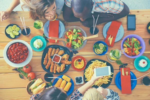 Gruppe von Menschen beim gemeinsamen Abendessen am Holztisch — Stockfoto