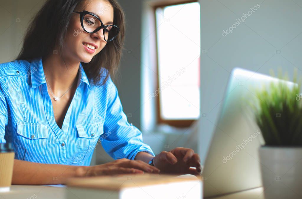 Young woman sitting in office table, looking at laptop computer screen