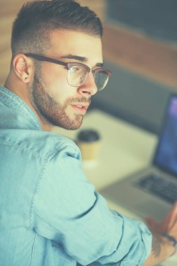 Genç adam kullanarak telefon ve dizüstü bilgisayarda çalışır