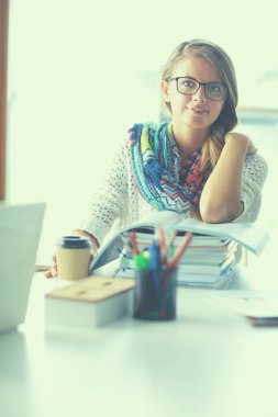 Kitapların arasında masa başında oturan genç bir kadın.