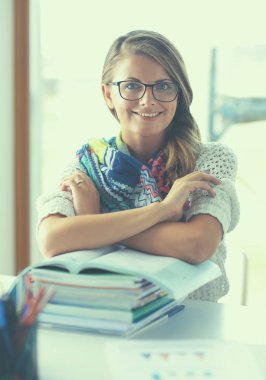 Kitapların arasında masa başında oturan genç bir kadın.