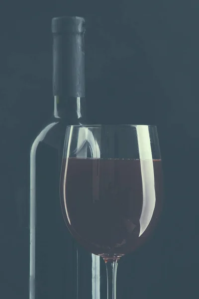 Verre de vin et une bouteille sur fond noir — Photo