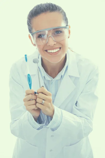 Hermosa doctora dentista femenina sosteniendo y mostrando cepillo de dientes aislado sobre un fondo blanco —  Fotos de Stock