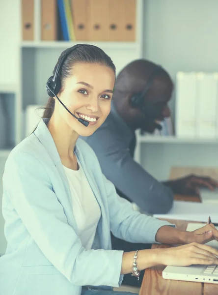 Mensen uit het bedrijfsleven met headsets computers gebruiken in office — Stockfoto