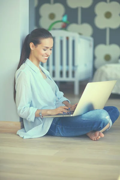 Giovane bella donna a casa seduta sul pavimento con il computer portatile — Foto Stock