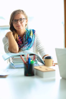 Kitapların arasında masa başında oturan genç bir kadın.